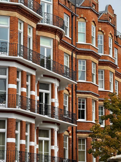 An exterior view of a multi-storey Victorian terrace building in West Kensington, featuring red brick facades with white stone accents and decorative elements. The building has several balconies with