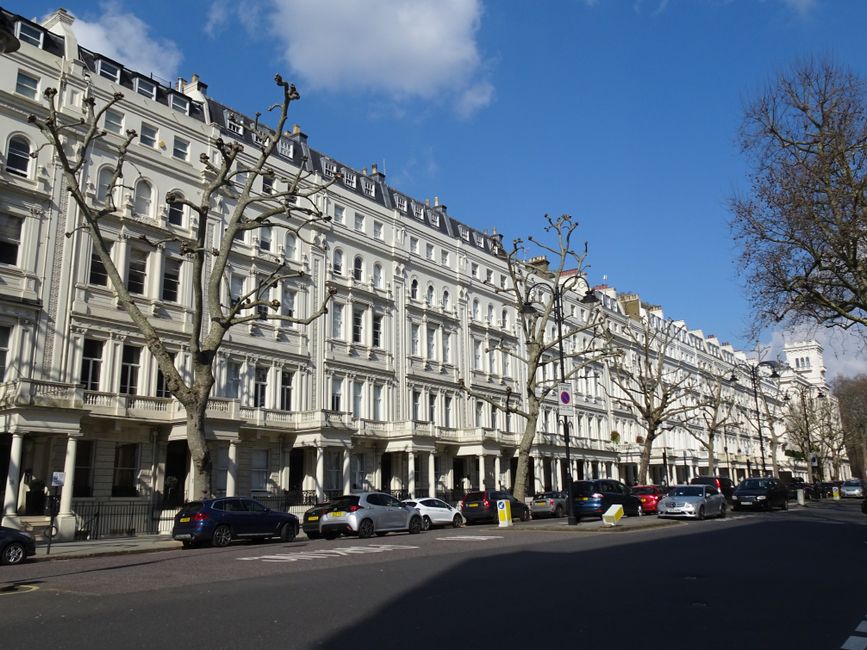 Inside a residential property, a removal team from West Kensington Removals is engaged in the furniture transport process. Several cardboard boxes and wrapped items are being carried across a tiled fl